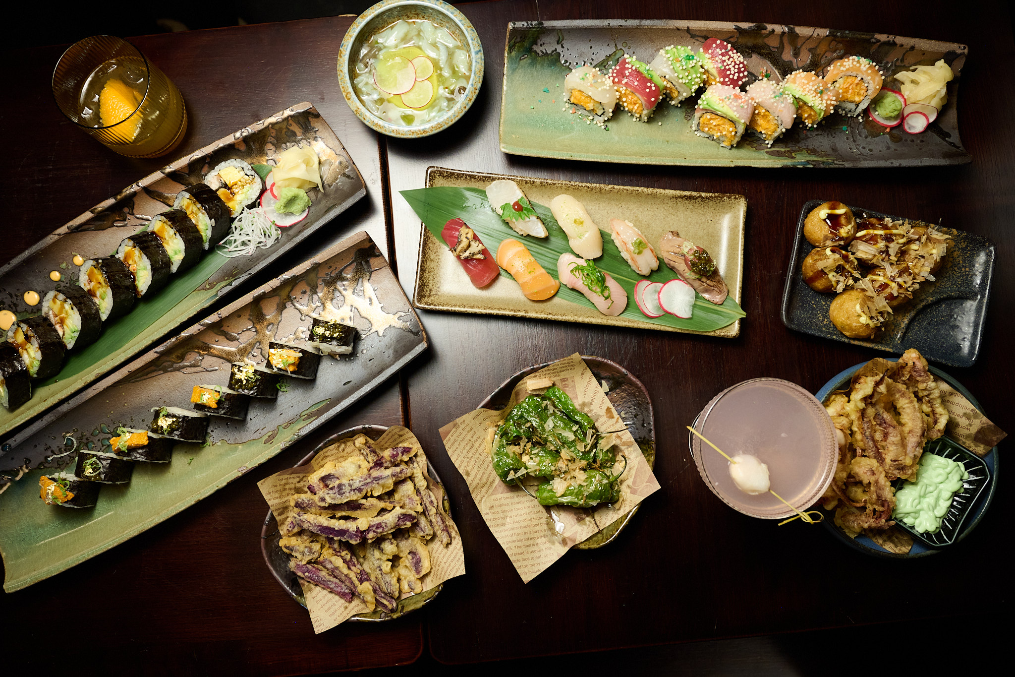 Overhead view of full Japanese izakaya table spread with sushi, rolls, tempura, and cocktails at Showa Era
