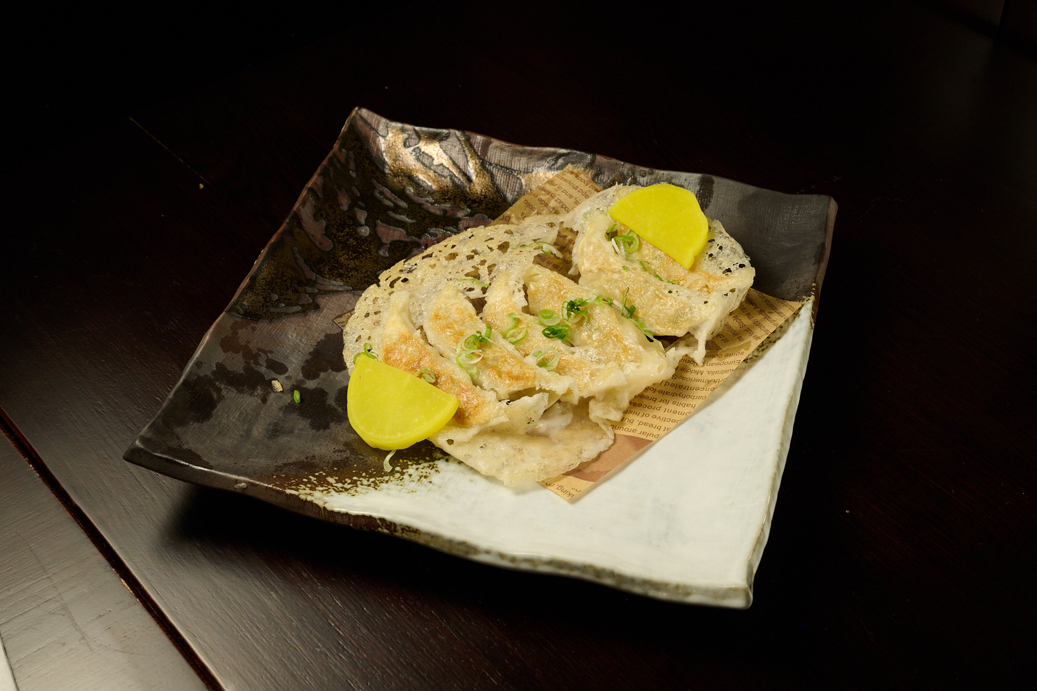 Pan-fried Japanese gyoza dumplings with crispy lace wings on artisan ceramic plate at Showa Era