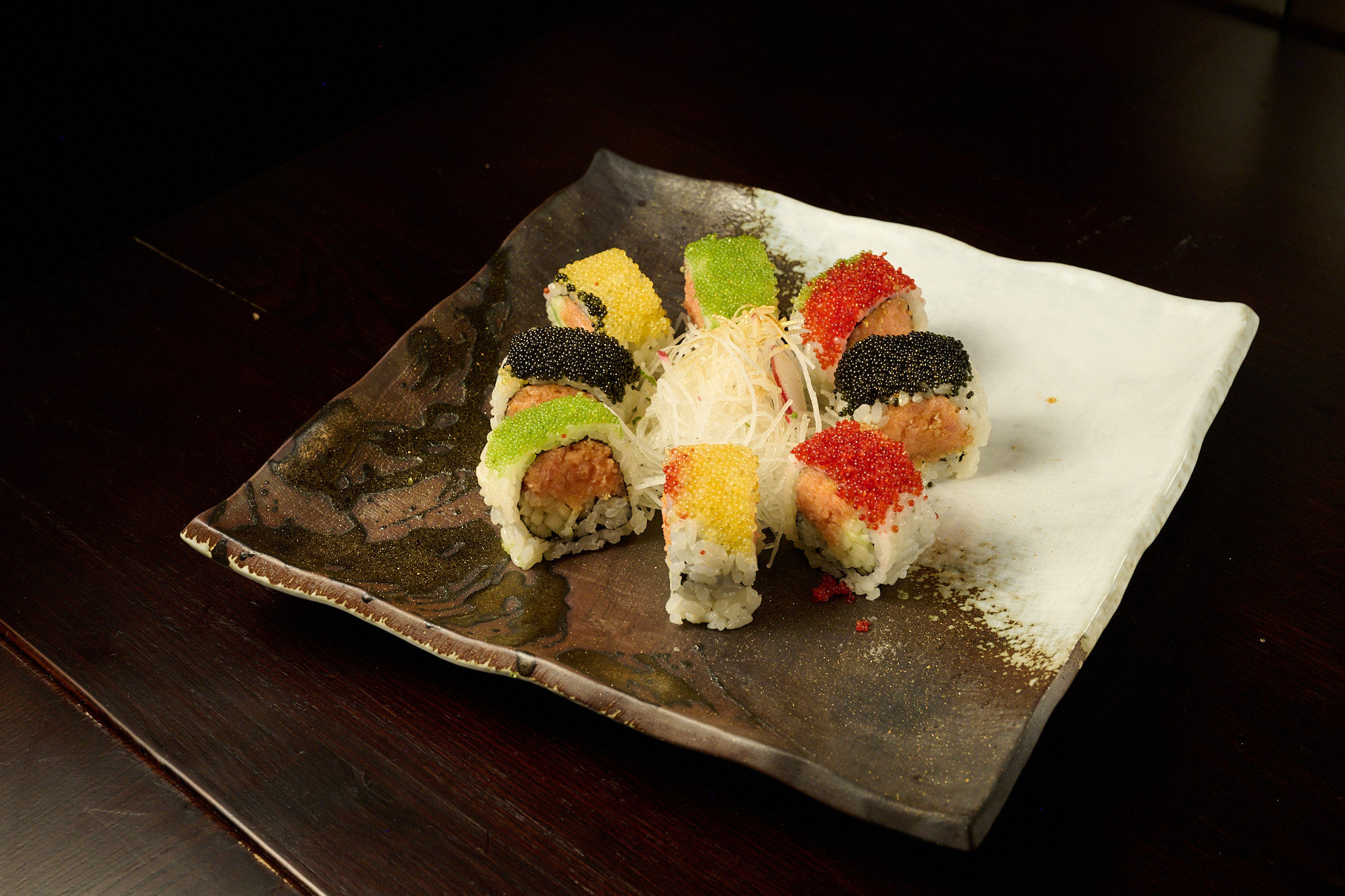 Artistic rainbow tobiko roll with multicolor roe on handcrafted ceramic at Showa Era