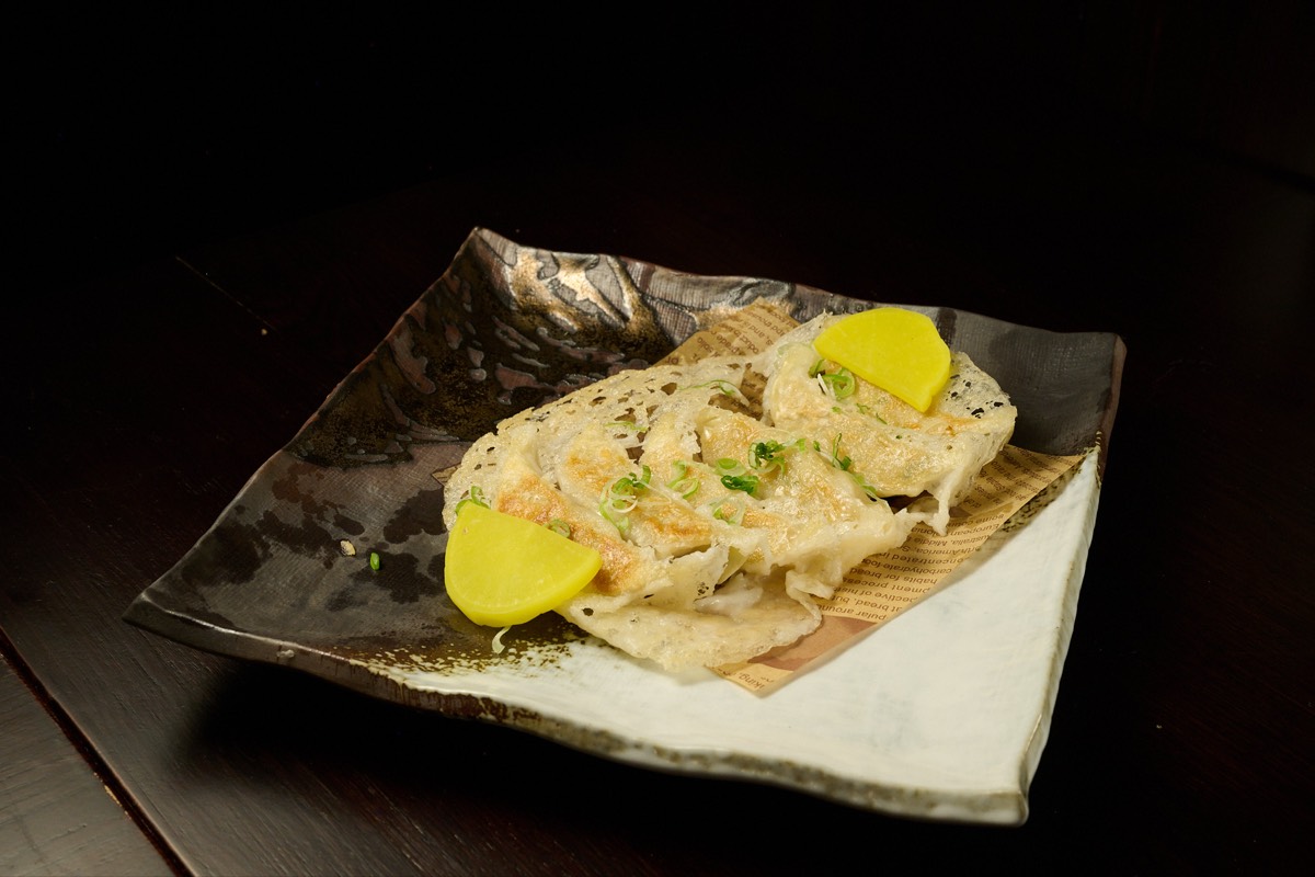 Pan-fried Japanese gyoza dumplings with dipping sauce at Hell's Kitchen izakaya